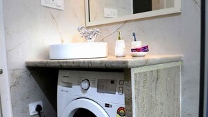 A compact laundry area with a washing machine, a sink, and a mirror.
