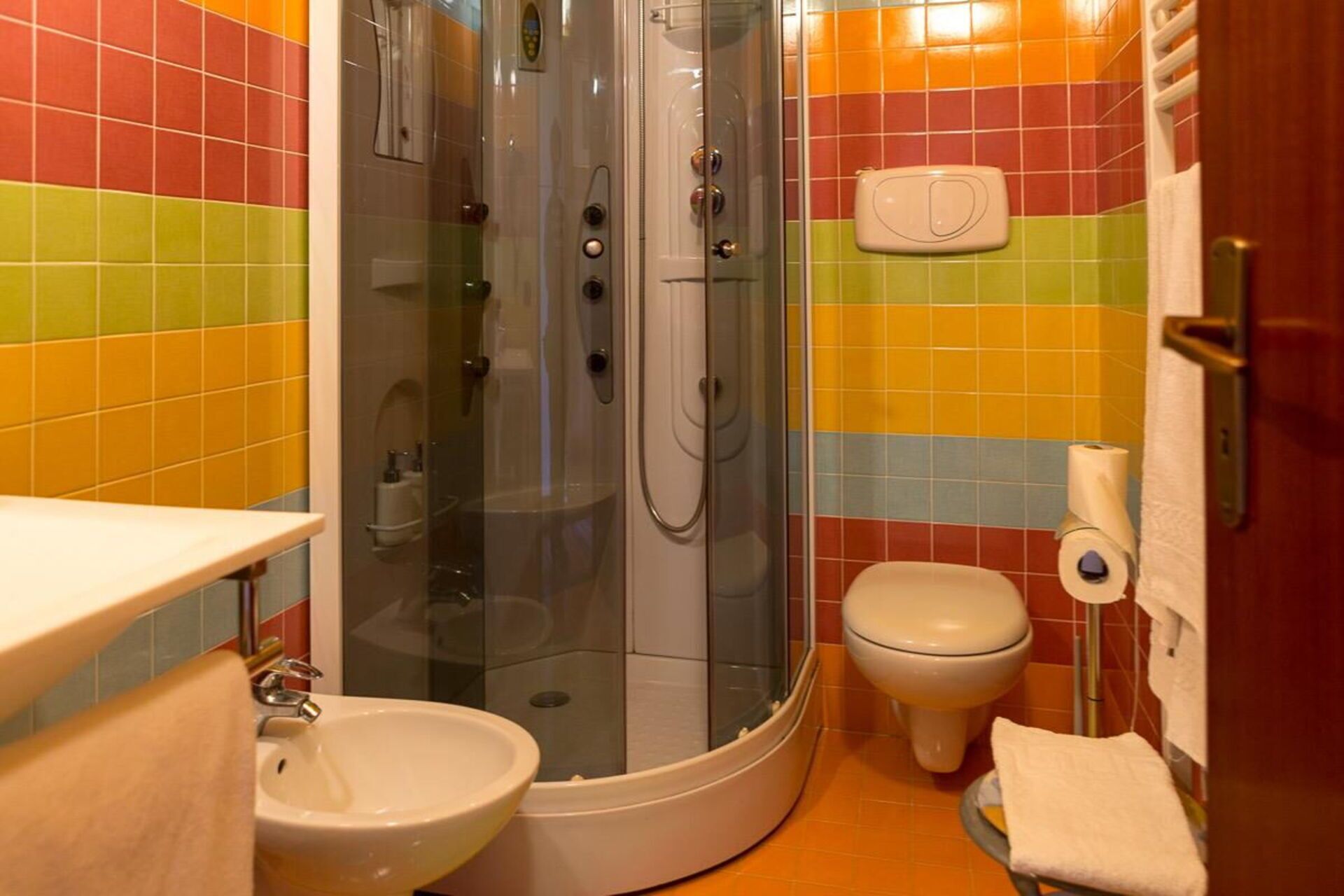 A bathroom with a glass-enclosed shower, a toilet, and a sink.