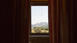 Una ventana con cortinas, vistas de una cordillera y una lámpara colgante.