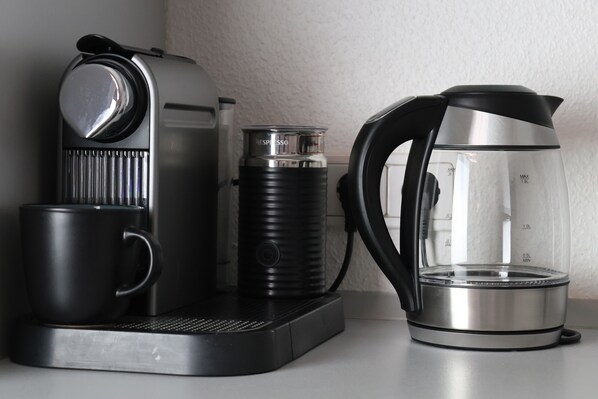 Une machine à café, un thermos et une carafe en verre sur un plan de travail.