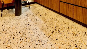 Una cocina moderna con armarios de madera, horno empotrado y comedor con mesa y sillas.