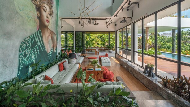 A spacious living area with a large window, a sofa set, and a mural on the wall. - Mandala Oasis (Bali)