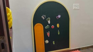 A room with a white wall, a black door with colorful vegetable stickers, and a blue and red foam floor. - VISHAL VILLA  (Jaipur)