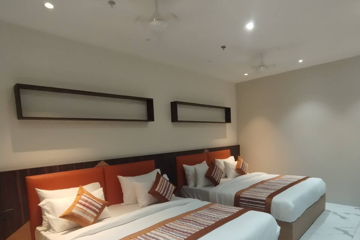 A hotel room with two beds, a wooden headboard, a marble floor, and a ceiling fan.