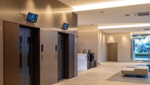 Eine moderne Lobby mit Aufzügen, einer Rezeption und einer Sitzecke.