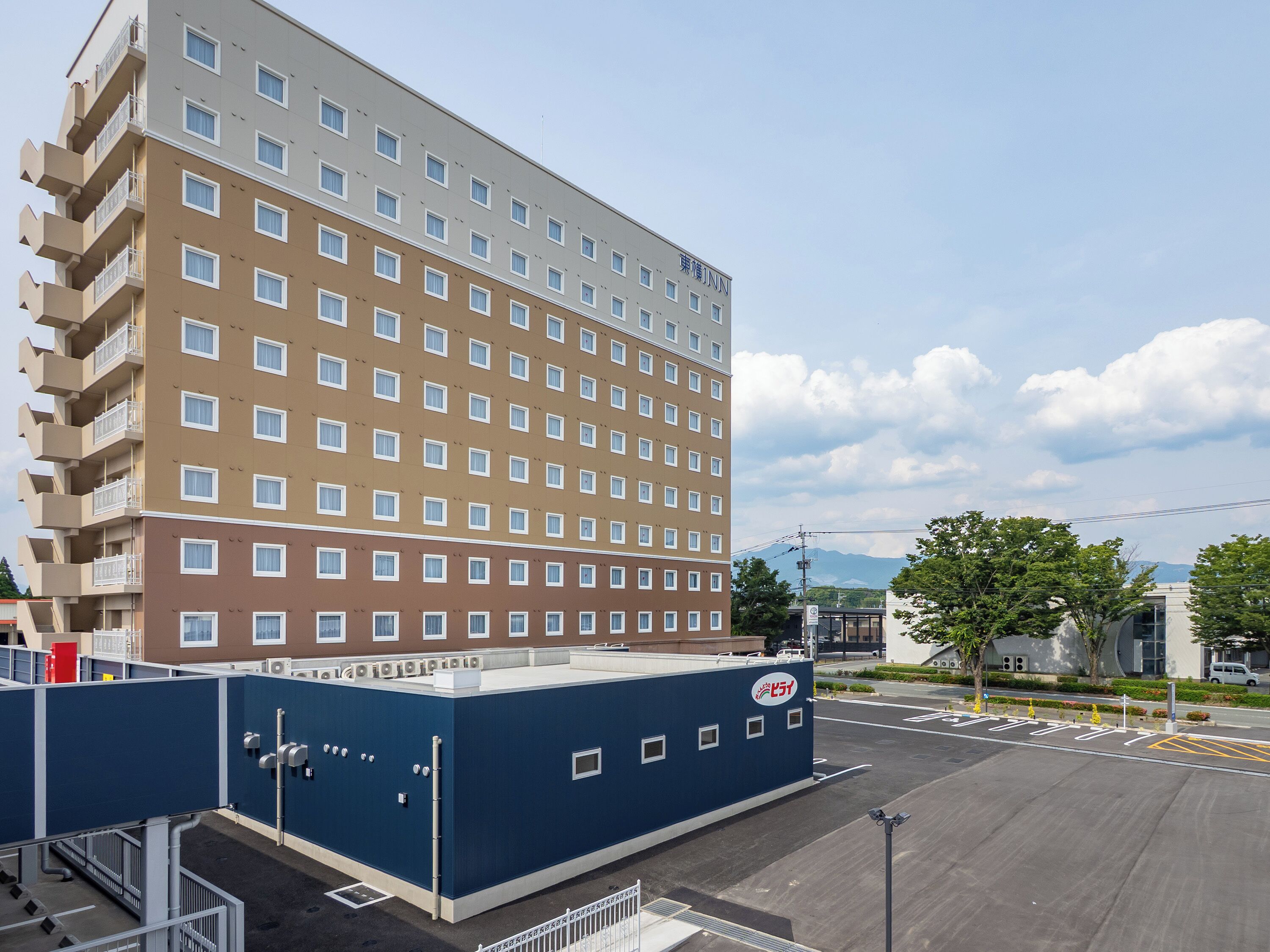 A multi-story hotel with a modern design, featuring a flat roof and a series of balconies.
