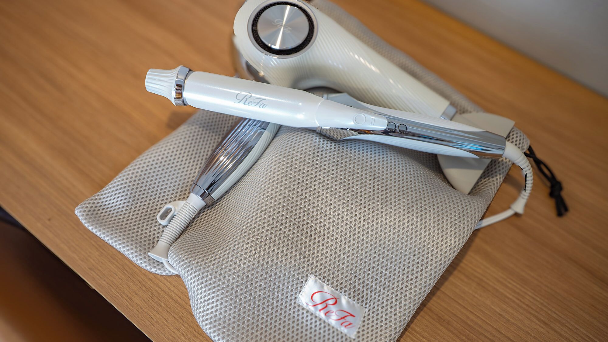 A hairdryer and a hairbrush on a wooden table.