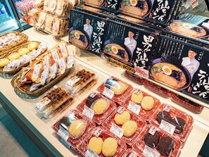 Variedad de alimentos envasados, como pan, galletas y comidas preparadas, exhibidos en un estante de tienda.