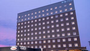 Ein mehrstöckiges Hotel mit modernem Design, das viele gleich große Fenster und ein flaches Dach aufweist.