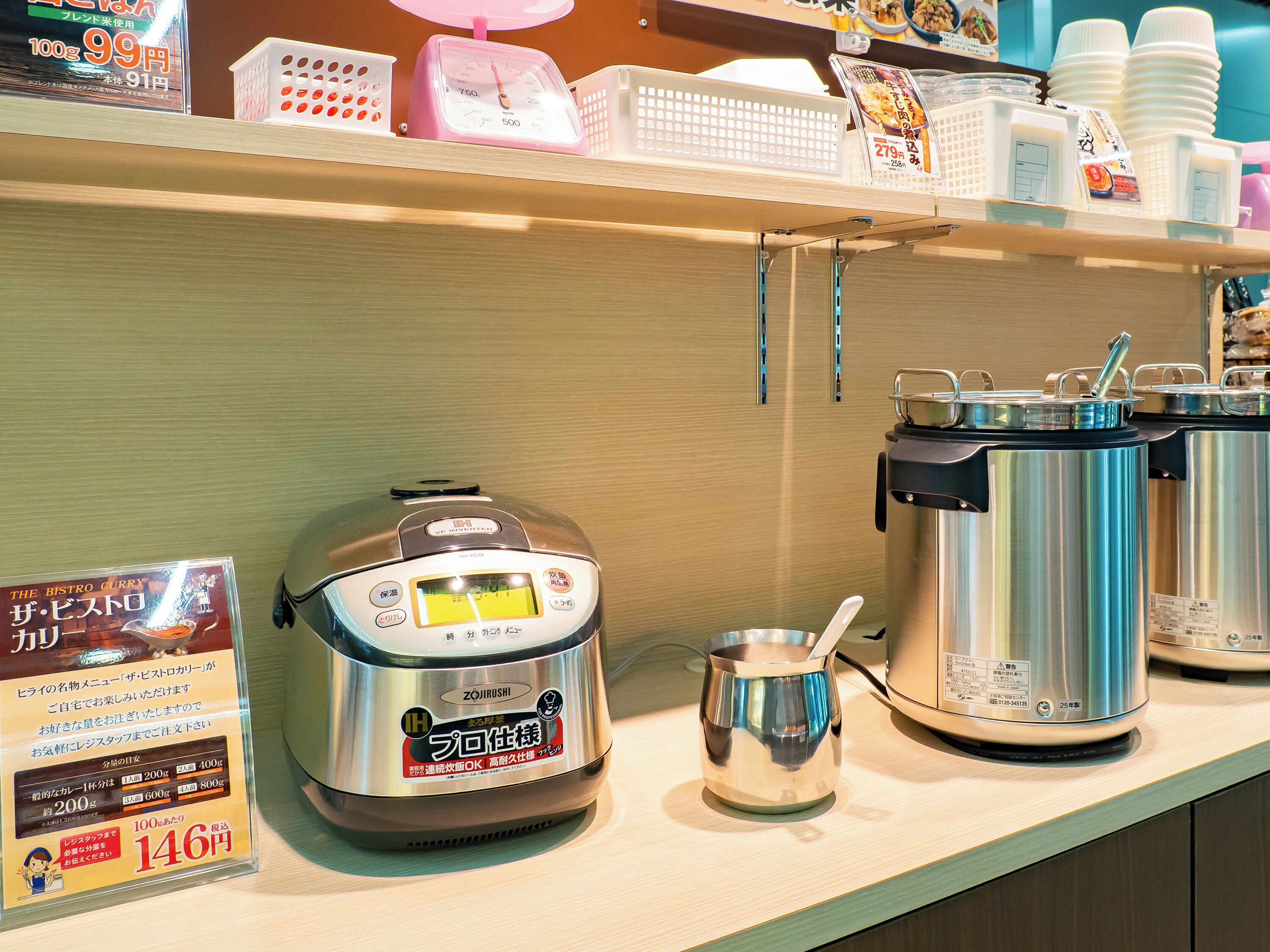 Una cocina con una cocedora de arroz, una olla y un recipiente pequeño sobre la encimera.