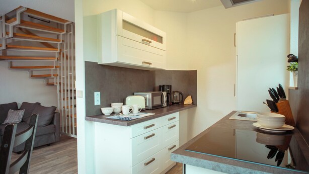 A compact kitchen with white cabinetry, a microwave, and a coffee maker. - Vacation cottage Ditzum (Ditzum)