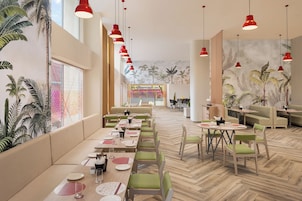 A spacious restaurant with high ceilings, red pendant lighting, and a herringbone floor pattern.
