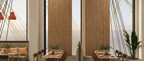 A modern dining area with wooden walls, green upholstered seating, and a herringbone floor pattern.
