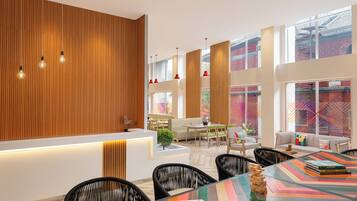 A modern dining area with a long wooden wall, multiple hanging red pendant lights, and a colorful striped table.