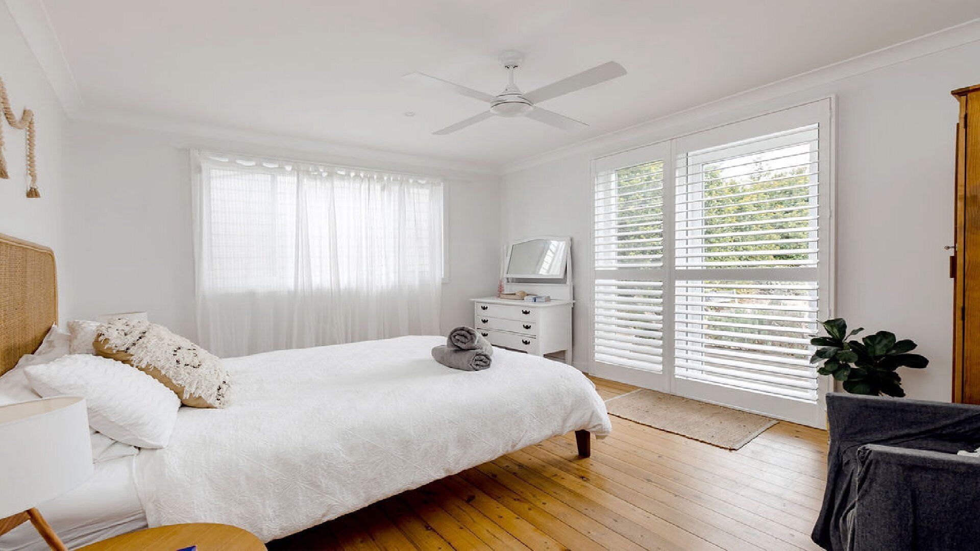 A bedroom with a bed, a dresser, a TV, and a ceiling fan.