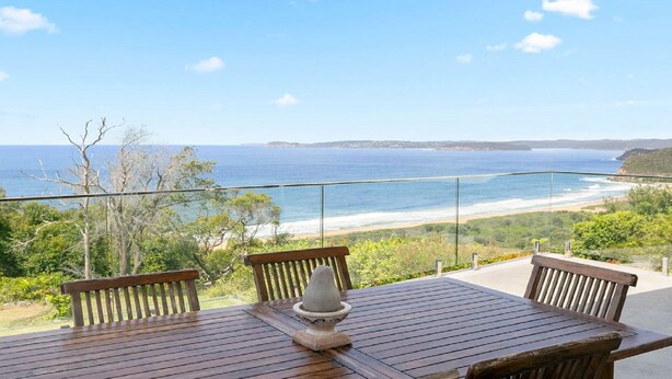 A wooden table with chairs on a balcony overlooking a beach. - Stunning ocean views and pool (KILLCARE HEIGHTS)