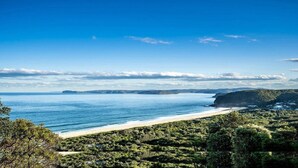 A coastal landscape with a beach, greenery, and distant hills. - Stunning ocean views and pool (KILLCARE HEIGHTS)