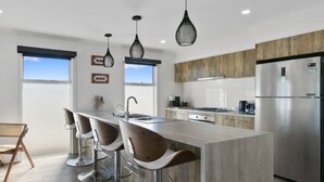 A modern kitchen with a central island, stainless steel appliances, and pendant lighting.