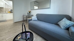 Een moderne woonkamer met een grijze bank, een salontafel met een boek, en een eethoek met een tafel en stoelen.