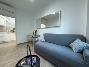 A modern living room with a grey sofa, a coffee table with a book, and a dining area with a table and chairs. - Spacious, luxury apartment with a view of the Duomo, accommodating 2+2+2 guests with privacy; rooftop elevator and Wi-Fi  (Firenze)