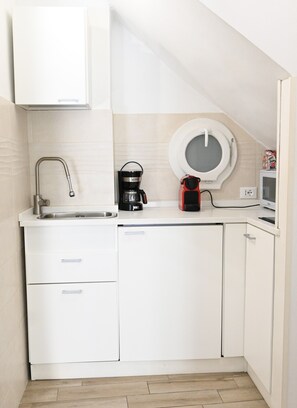 A compact kitchen with a sink, coffee maker, and microwave.