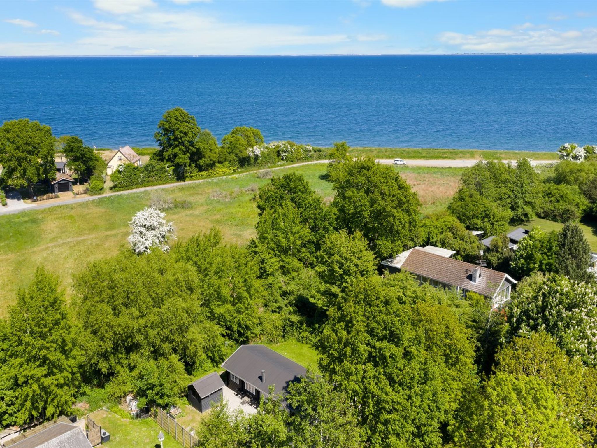 Vista aérea de una zona residencial con casas rodeadas de vegetación exuberante y vista al mar.