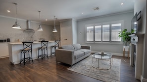 Relax in this stylish living space with a kitchen area, comfortable sofa, and large window.