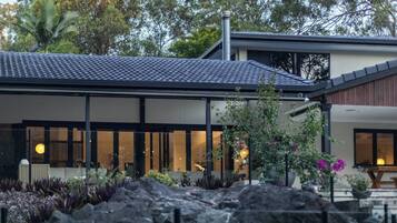 A modern house with a tiled roof, large windows, and a garden with rocks and plants.