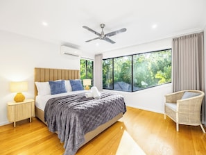 A modern bedroom with a bed, bedside table, lamp, and a chair. - Pool, Tennis & Cinema! 7Beds Bali-Inspired Retreat (Chapel Hill)