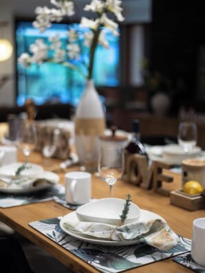 A dining table set with plates, glasses, and a vase with flowers. - Pool, Tennis & Cinema! 7Beds Bali-Inspired Retreat (Chapel Hill)