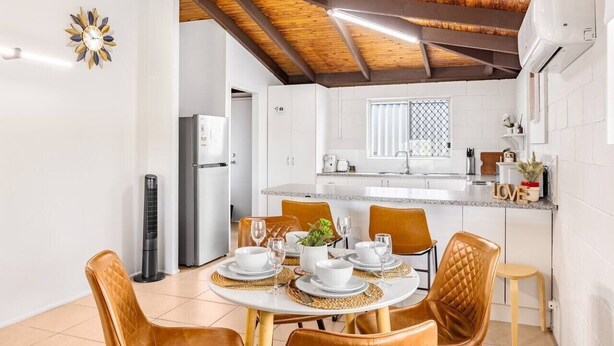 Un espace repas avec une table ronde, des chaises et une cuisine en arrière-plan.
