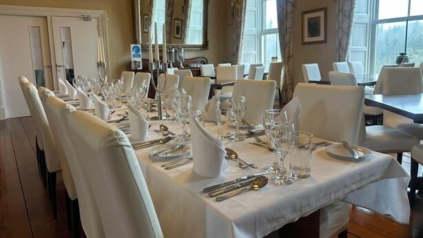 A dining area with tables set for a meal, chairs, and a chandelier. - Newcastle House Hotel (Ballymahon)