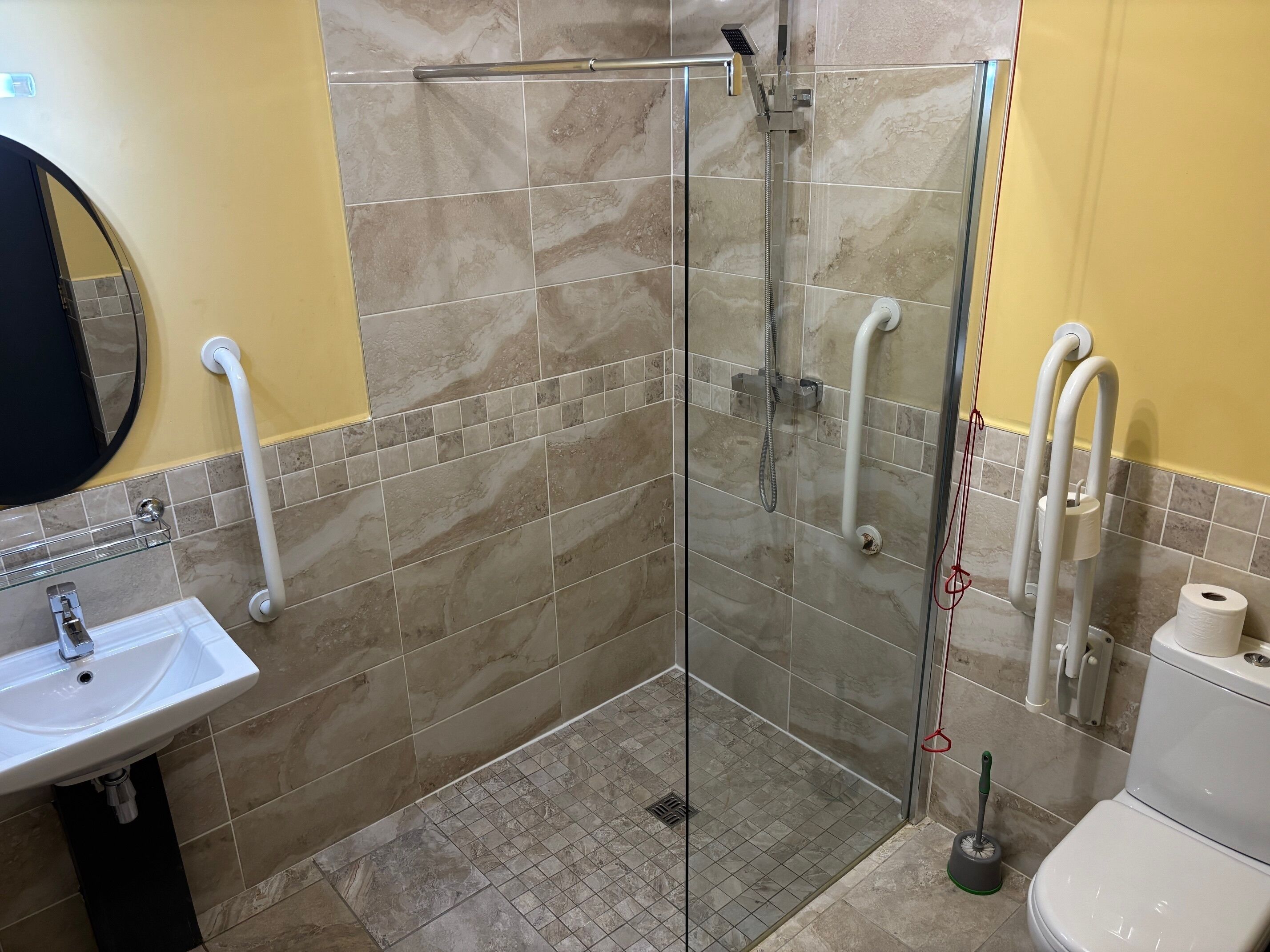 A bathroom with a glass shower enclosure, a sink, and a toilet.