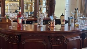 A bar area with a wooden counter, a bottle of Aperol, a copper mug, and various glassware. - Newcastle House Hotel (Ballymahon)