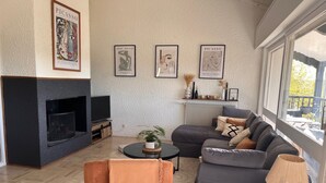 A modern living room with a fireplace, a sofa set, a coffee table, and framed artwork on the walls. - Spacious country house, 15 min from Bordeaux city center (Latresne)