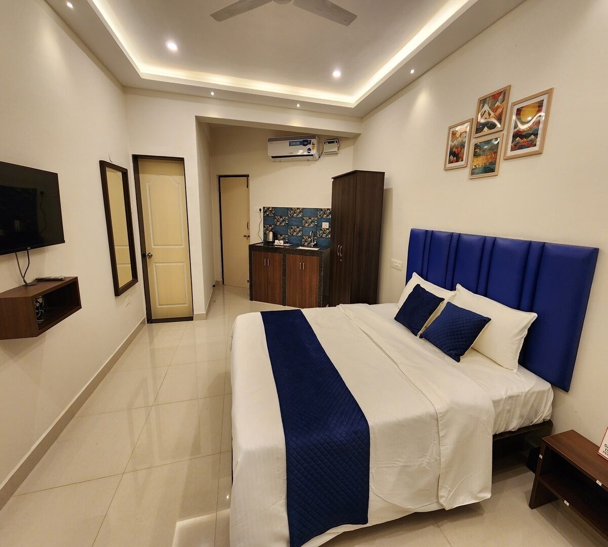 Habitación de hotel con cama, televisión, minibar, baño y kitchenette.