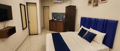 Habitación de hotel con cama, televisión, minibar, baño y kitchenette.