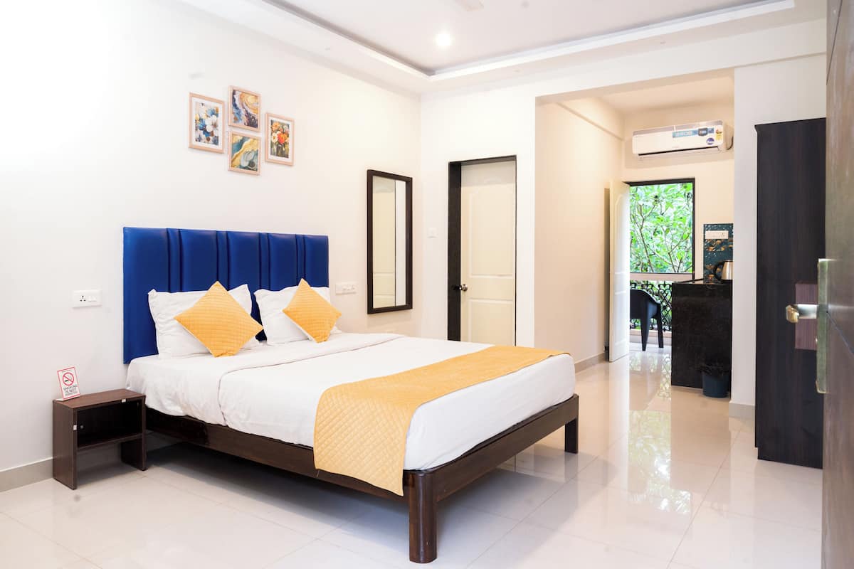 A hotel room with a large bed, a nightstand, a mirror, and a door leading to a balcony.