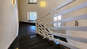 A staircase with a white railing, black marble steps, and a chandelier.