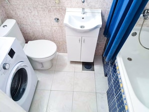 A bathroom with a washing machine, toilet, sink, and bathtub. - Room-angelina Apartment 3 (Belgrade)