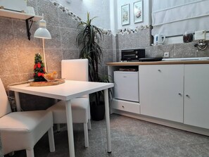 A modern kitchen with white cabinets, a small dining table, a Christmas tree, and a Tesla refrigerator. - Room-angelina Apartment 3 (Belgrade)
