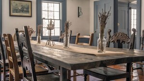 Een eetkamer met een lange houten tafel, stoelen en decoratieve vazen.