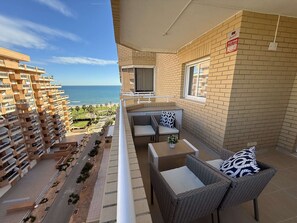 A balcony with wicker furniture, a TV, and a view of the ocean.