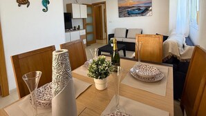 A modern living room with a dining area, featuring a sofa, a coffee table, and a painting of a sunset. - CB250 - Cala Blanca II, Superior - ServHouse (Orpesa)