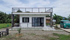 Una casa moderna de dos pisos amb un balcó, un jardí petit i un cotxe aparcat.