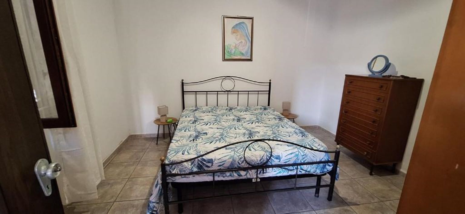 Une chambre à coucher avec un lit, une commode, une table de chevet et un tableau accroché au mur.