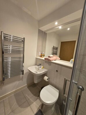 A modern bathroom with a glass shower enclosure, a white sink, and a toilet. - Home Away From Home in Manchester! (Salford)