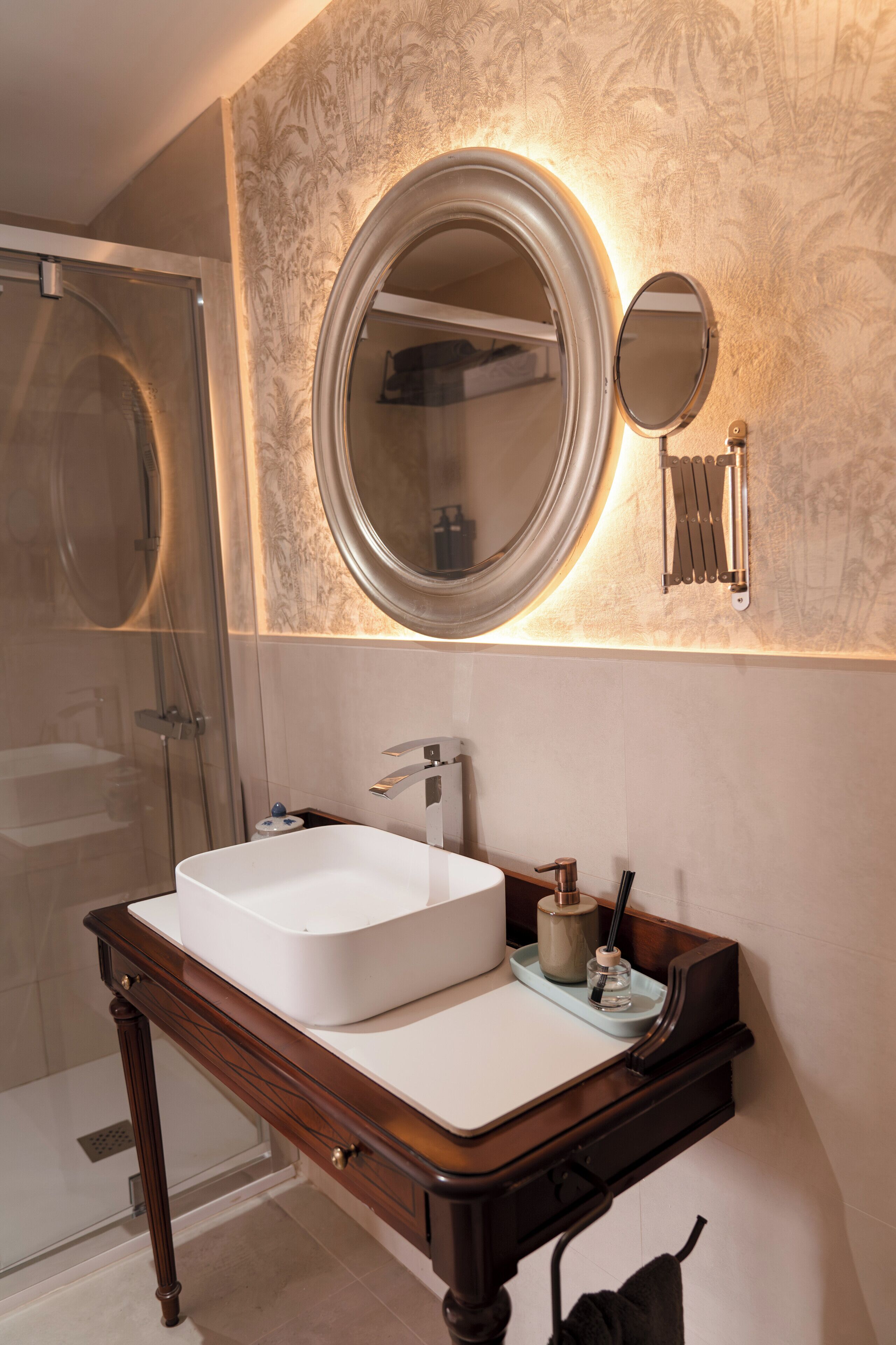 A bathroom with a large mirror, a white sink, and a shower.
