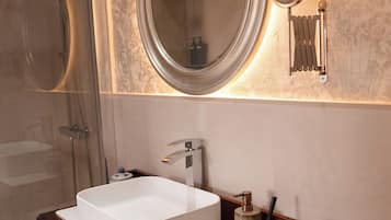 A bathroom with a large mirror, a white sink, and a shower.