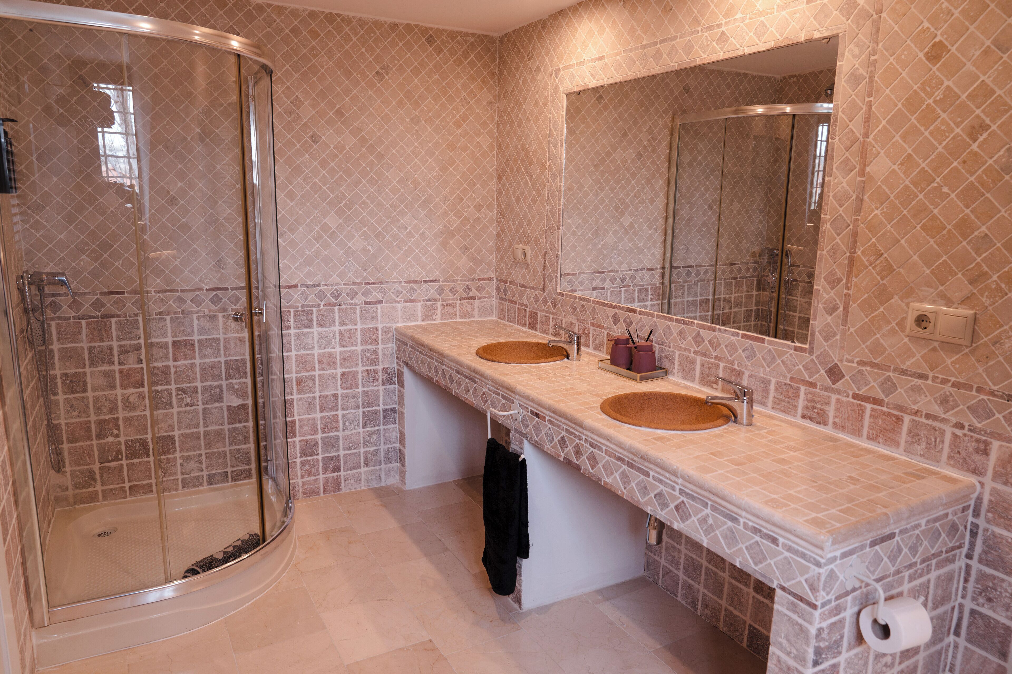 Un baño con dos lavamanos, cabina de ducha de vidrio y un espejo grande.